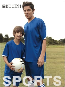 A man and boy wearing matching blue sports kits, holding a football, standing on a grassy field. The image features a logo.