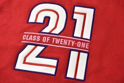 A red fabric with large white and blue embroidered numbers "21" and the text "CLASS OF TWENTY-ONE" underneath.