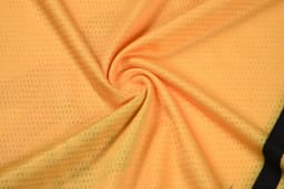 A yellow fabric featuring a textured pattern, arranged in a spiral formation. The fabric has a black section along the edge and includes branding.