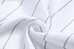 A textured fabric in white with subtle grey stripes, highlighting the material of cropped pants. It features a logo.