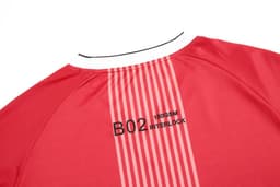 A red long-sleeved crew top featuring a white collar and a logo on the back. It has striped design elements.