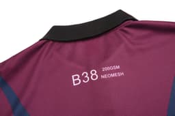 A polo shirt in maroon with a black collar, featuring a branded logo and details on the fabric type.