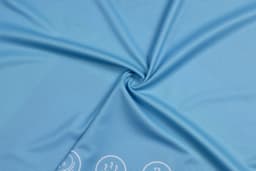 A light blue fabric with a smooth texture and a logo along the bottom edge.