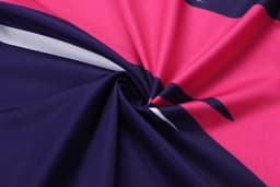 A swirl of fabric in pink, navy, and white, showcasing a smooth texture and vibrant colours. Features branding.