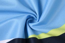 A blue and black fabric showcasing a textured pattern, with green accents visible in the design.