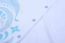 A white shirt featuring a blue floral design, with light blue buttons along the placket.
