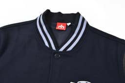 A navy blue letterman jacket featuring a striped collar and a logo on the front.