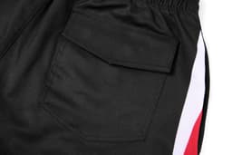 A pair of black woven long shorts featuring side pockets and a contrasting red and white stripe.