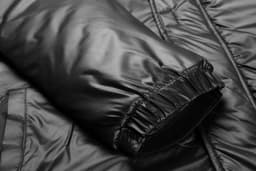 A black manager coat jacket featuring a smooth, padded texture and elasticated cuffs.