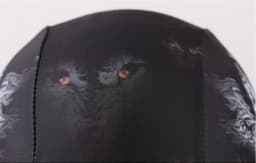 A black swimming cap featuring a graphic design with fierce eyes and a textured pattern. It has a logo.
