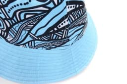 A reversible bucket hat with a blue and black abstract pattern and a wide brim. It includes a logo.