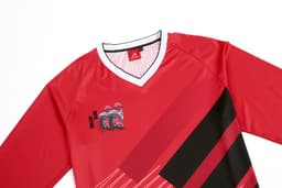 A red long-sleeve crew top with black and pink graphic designs and a logo on the collar area.