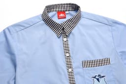 A blue school shirt with a checkered black and white collar and an embroidered design on the pocket.