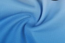 A fabric swirl showcasing light blue material, featuring a smooth texture. The image includes a logo in a corner.