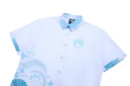 A light blue school wear shirt featuring a decorative design and a logo on the chest area.
