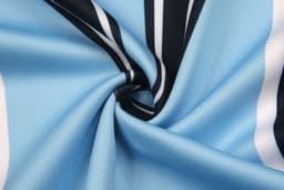 A close-up of fabric in light blue, featuring black and white stripes with a smooth texture. It has a logo.