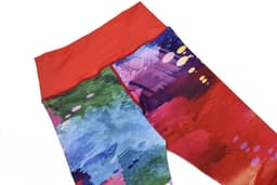 A pair of vibrant leggings featuring a blend of red, green, and blue abstract patterns with a solid red waistband.