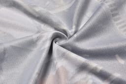 A close-up of light grey fabric with a smooth texture, featuring a subtle, patterned design and a logo.