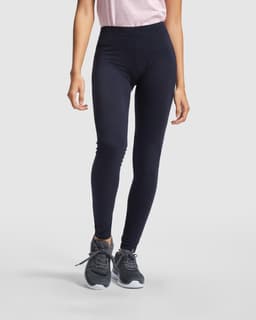 Navy leggings featured, paired with a light pink top and grey athletic shoes. The image has a branding logo.
