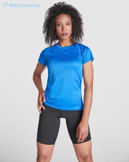 A blue women's T-shirt made from moisture-wicking fabric, paired with black shorts, featuring a logo.