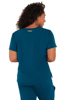 A woman wearing a teal top, viewed from the back, with a logo on the garment.