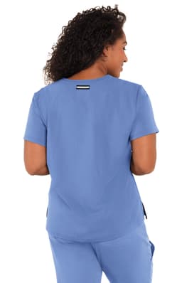 A woman wearing a blue top, showcasing the back design. The top features a logo on the upper back.