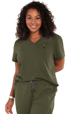 A woman smiles while wearing a green "Ready to Work Top" with a pocket and a logo. The fabric appears comfortable.