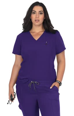 A purple medical top with a V-neck and short sleeves, featuring a logo. The model poses confidently in scrubs.