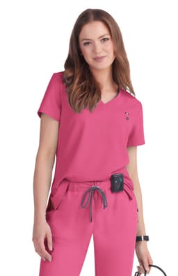 A pink medical top with a V-neck design, paired with matching scrubs. The model is accessorised with a small device.