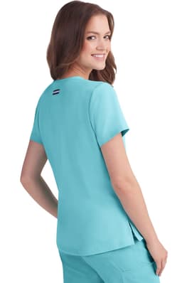 A woman in a turquoise short-sleeved top smiling over her shoulder, featuring a small logo on the back.