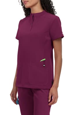 A maroon medical scrub top with a short collar and two front pockets. It has a logo on the sleeve.