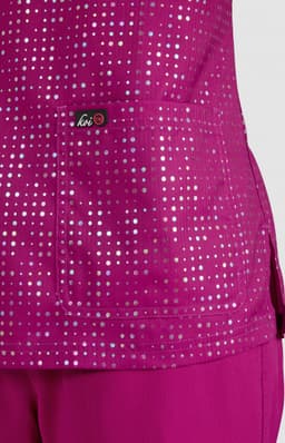 A vibrant fuchsia top featuring a pocket, adorned with a pattern of reflective dots, with a logo present.