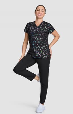 A woman is wearing a black patterned top with various colours, paired with black pants and white shoes.