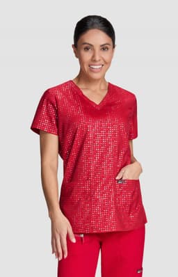 A woman wearing a red printed top, featuring a V-neck and two front pockets, complemented by red pants.