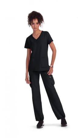 A woman wearing a black scrubs outfit, featuring a short-sleeve top and cargo pants, standing with hands on her hips.