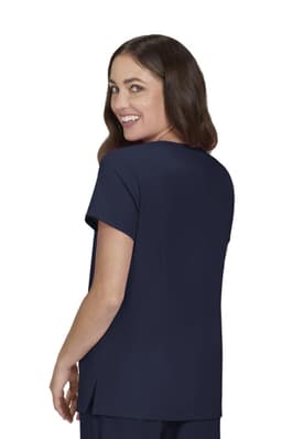 A woman wearing a navy top with a short sleeve and a relaxed fit, looking back and smiling.