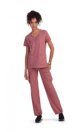 A set of scrub clothing in dusty pink, featuring a short-sleeve top with pockets and matching pants.