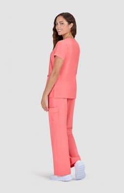 A woman wearing a vibrant coral scrub set with a relaxed fit, featuring a top and cargo-style trousers.