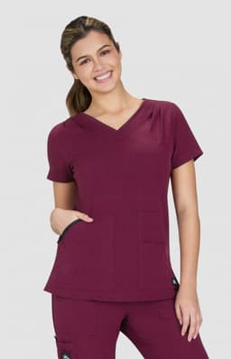 A burgundy Sari Top featuring a V-neck design and two front pockets, worn by a smiling model.