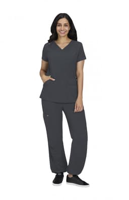 A woman wearing a charcoal grey medical scrubs set, featuring a V-neck top and matching pants, stands smiling.