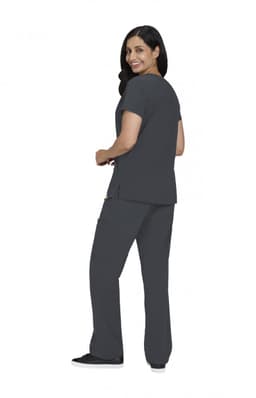 A woman wearing a grey Sari Top and matching cargo pants, smiling and seen from the back. The outfit has a logo.