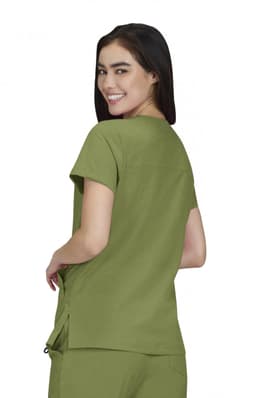 A woman wearing an olive green Sari Top, showcasing the back view of the shirt. The product has a logo.