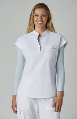 A white top with short sleeves and a front pocket, worn by a smiling woman against a neutral background.