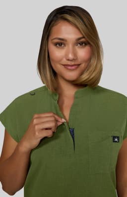 A green Catrin Top featuring a collar and a zippered neckline, paired with a logo.