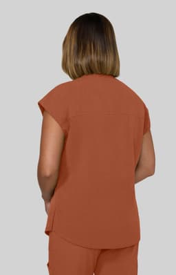 A back view of a woman wearing an orange, short-sleeved top made from a lightweight fabric.