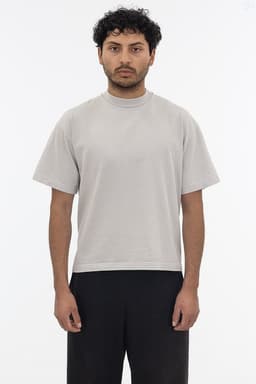 A short sleeve garment dye T-shirt in light grey, displayed on a model. The shirt has a simple design and a logo.