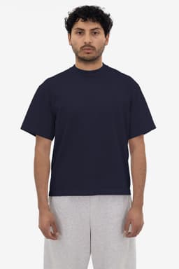 A navy short sleeve garment dye t-shirt displayed on a model, paired with grey shorts. The t-shirt features a logo.