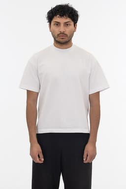 A plain white short sleeve garment dye T-shirt displayed on a model, featuring a simple design and relaxed fit.