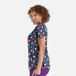 A women's v-neck top featuring a colourful print of various dogs against a dark background. The top has a logo.