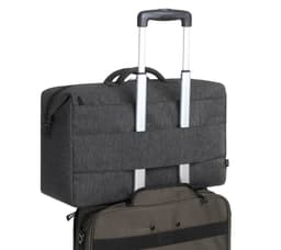 A dark grey duffle bag atop a wheeled suitcase, featuring a handle and logo.